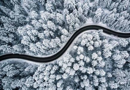 Aerial view of a winding road through a snow-covered forest, symbolising Lenvi's expertise in loan management software