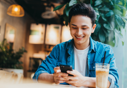 Smiling Gen Z man using a smartphone, representing borrowing challenges and better outcomes