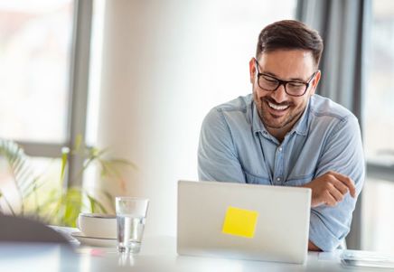 Smiling man using a laptop, representing technology's role in fraud prevention for SME receivables finance - Lenvi Insights